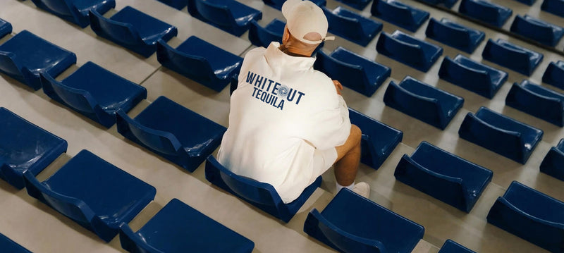 Person sitting in an empty stadium with a 'Whiteout Tequila' sweatshirt.