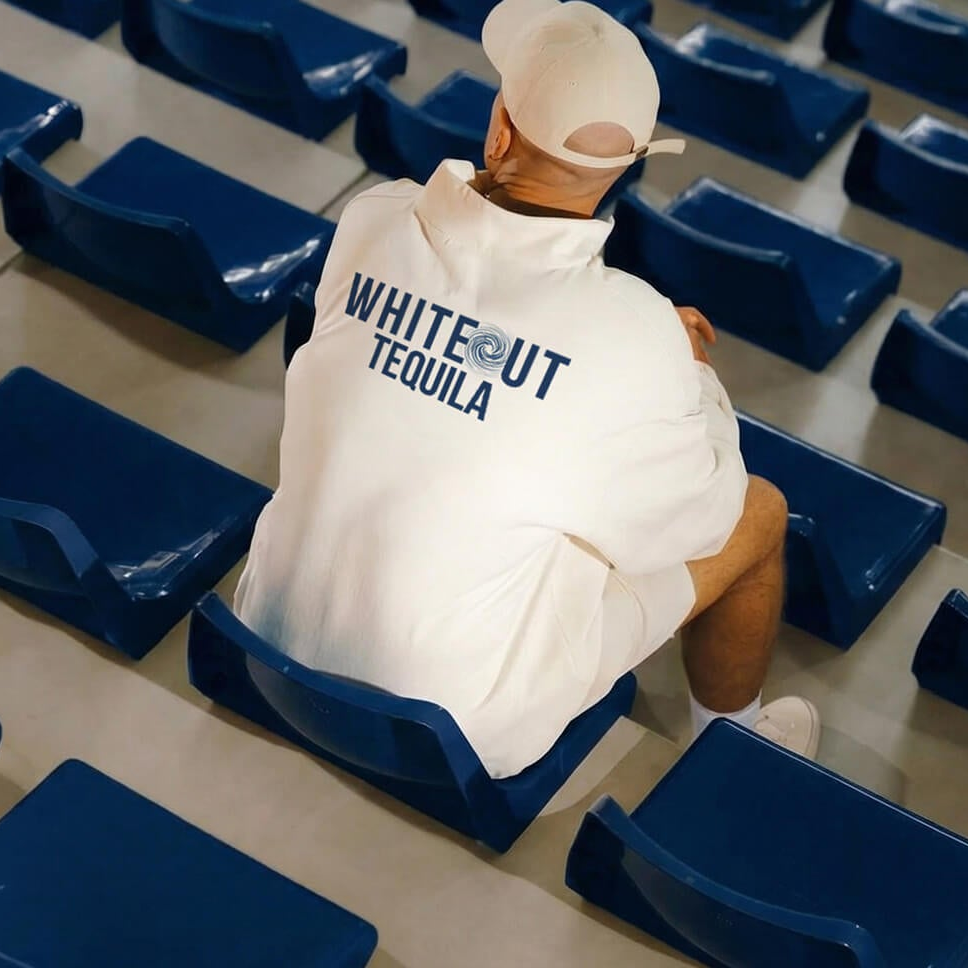 Person sitting in an empty stadium with a 'Whiteout Tequila' sweatshirt.
