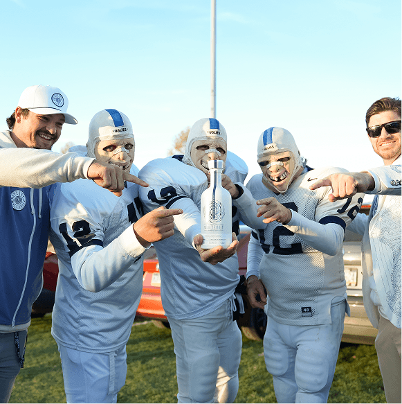 Group of people in football uniforms holding a bottle of whiteout on a field