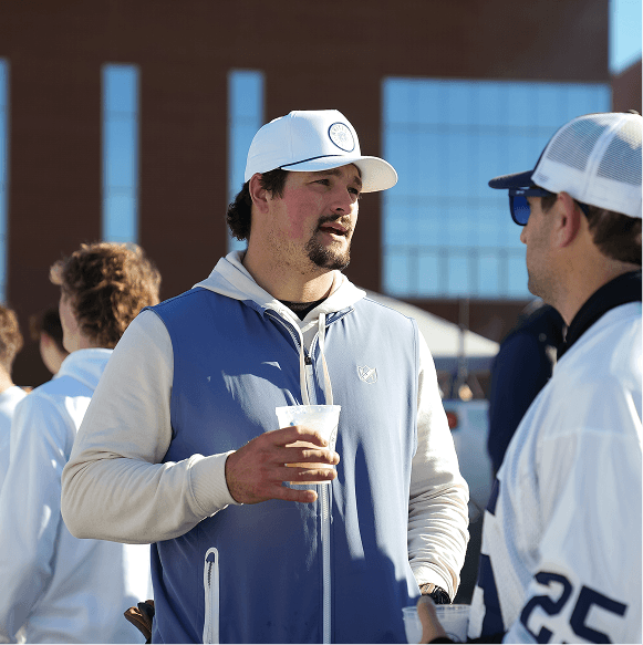 Two men in sports attire talking outdoors with a blurred background