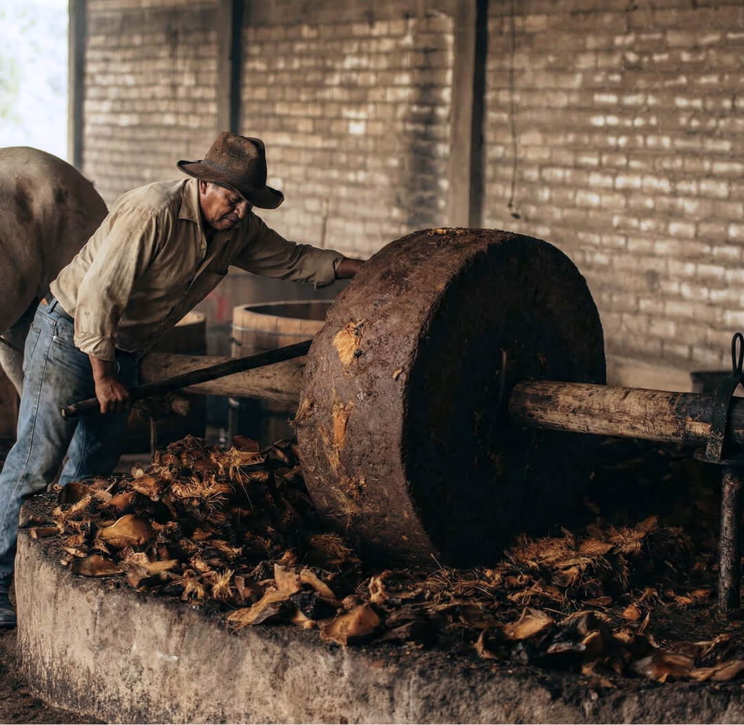 Man working with large wheel and wooden platform in rustic setting